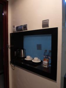a tv in a room with two cups and water at Bahagia Hotel Langkawi in Kuah