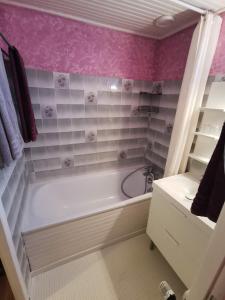 uma casa de banho com uma banheira branca e azulejos cor-de-rosa em La maison de Céline em Arry