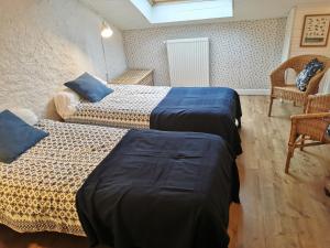 a room with two beds with blue sheets and a chair at La maison de Céline in Arry