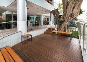 una terraza de madera con un árbol y bancos frente a un edificio en Centromar Hotel, en Balneário Camboriú