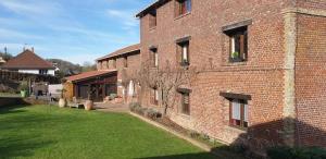 a brick building with a green lawn in front of it at Hôtel Restaurant l’Éolienne in Rouxmesnil-Bouteilles