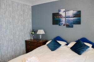 a bedroom with a bed with four paintings on the wall at Bryn Noddfa in Morfa Nefyn