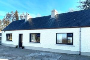 a white house with black windows and a roof at Grogagh Hill Cottage in Sligo