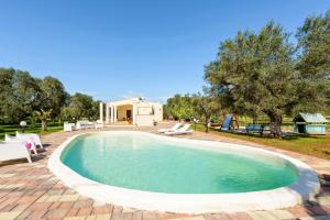 a swimming pool in a yard with chairs and a house at Villa Käthe con Piscina Privata in San Vito dei Normanni