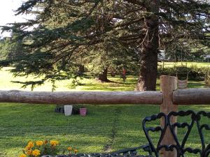 a wooden fence in a park with a tree at Cabañas Cuncumen in Tandil