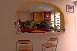 a kitchen with an arch over a counter and two chairs at Le lit d'Oli in Sainte-Rose