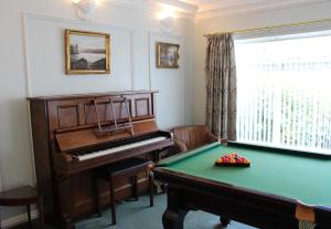 a room with a piano and a green table at Bryn Noddfa in Morfa Nefyn