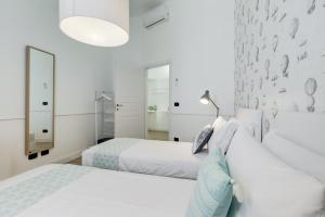 - une chambre blanche avec 2 lits et un miroir dans l'établissement BMGA l Glam Industrial 3-Bed Apartment in Termini, à Rome