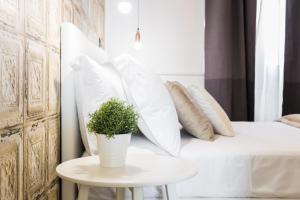 - un lit blanc avec des oreillers et une plante en pot sur une table dans l'établissement BMGA l Glam Industrial 3-Bed Apartment in Termini, à Rome