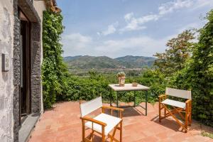 una mesa y sillas en un patio con montañas al fondo en Fondo Cipollate, en Castiglione di Sicilia
