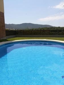 een groot blauw zwembad met bergen op de achtergrond bij Apartamento con Piscina in Llança