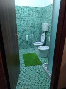 a bathroom with a toilet and a green tile floor at Monolocale sulle piste alle Polle in Riolunato
