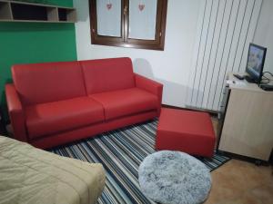 a living room with a red couch and a stool at Monolocale sulle piste alle Polle in Riolunato