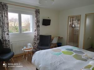 a bedroom with a bed and a chair and a window at Hôtel Le Poulmic in Lanvéoc