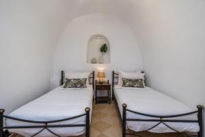 two twin beds in a room with a side table at Amore Villa in Karterados