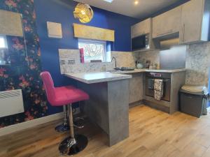 a kitchen with a counter and a pink stool at Park House Studio in Matlock