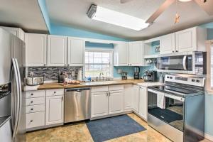 a kitchen with white cabinets and stainless steel appliances at Surfside Beach Gem with Deck - 1 Block to Shore! in Freeport