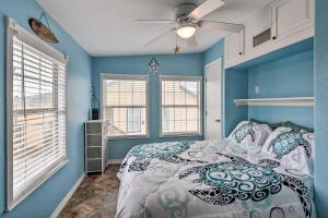 a blue bedroom with a bed and two windows at Surfside Beach Gem with Deck - 1 Block to Shore! in Freeport