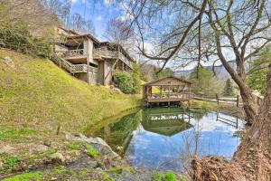a house on top of a hill next to a pond at Best Location - Maggie Valley Cabin with Hot Tub! in Maggie Valley