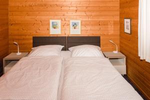 two beds in a bedroom with wooden walls and two lamps at Kastanienhof in Kalleby