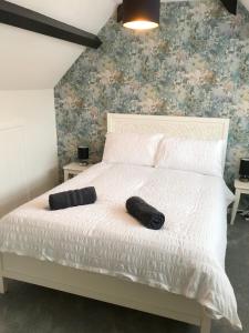 a white bed with two black pillows on it at The Beach Hut - 1 Bedroom Apartment Near the Beach in Bournemouth