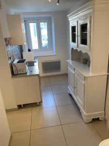 a kitchen with white cabinets and a tiled floor at MSM locations in Luxeuil-les-Bains