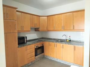 a kitchen with wooden cabinets and a sink and a microwave at OceanBlue Modern king size 1 Bedroom Apartment with Seaview and Terrace in Chayofa