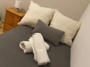 Una cama con toallas blancas y almohadas. en Apartamento Turistico San Cristobal, en Plasencia