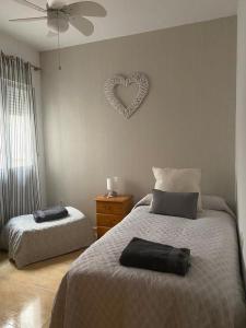 1 dormitorio con 2 camas y un corazón en la pared en Apartamento Turistico San Cristobal, en Plasencia