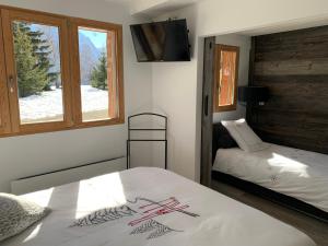 a bedroom with two beds and a television and a window at Mon nid montagnard au soleil in Les Deux Alpes