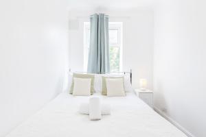 a white bedroom with a bed with white pillows and a window at Charming 3-Bed Apartment in Romford in Romford