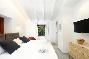 a white bedroom with a large bed and a flat screen tv at Jaume Ramona in Pollença +22 photos
