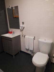 La salle de bains est pourvue de toilettes blanches et d'un lavabo. dans l'établissement Leiria Village casa bungalow, à Leiria