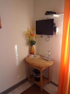 uma pequena mesa com um vaso de flores e uma televisão em Sauerland-Hotel em Essentho
