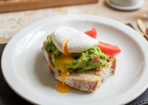 a white plate with a sandwich with an egg on it at The Briarfields in Torquay
