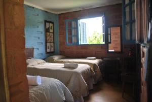 Cette chambre comprend 3 lits et une fenêtre. dans l'établissement Hostel da Montanha, à Campos do Jordão