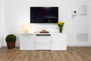 a white entertainment center with a tv on a white wall at La Casa del Campo de Mis Rapaciños in Alhaurín el Grande