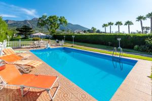 a swimming pool with two lawn chairs and a swimming poolvisor at La Casa del Campo de Mis Rapaciños in Alhaurín el Grande