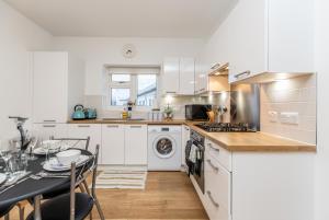ダートフォードにある2BR Apt-Sleeps 5-Accessible-Central Dartfordのキッチン(白いキャビネット、テーブル付)、ダイニングルーム