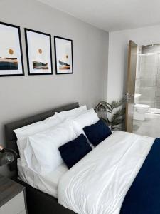 a white bed with blue pillows in a bedroom at The Panda - Modern 2 Bedroom Apt in Manchester City Centre in Manchester
