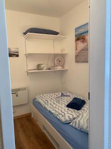 a small bedroom with a bed and shelves at Appartement mit Balkon und Meerblick in Fehmarn