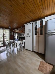 a kitchen with white appliances and a table with chairs at Hospedagem Chalé pousada Chácara Cantinho do Mozão in São Roque