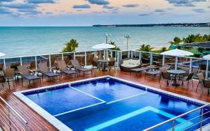 a balcony with a swimming pool and chairs and the ocean at Laguna Praia Hotel in João Pessoa
