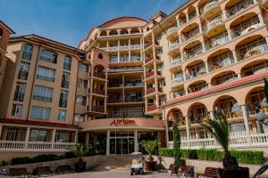 un gran edificio de apartamentos con balcones y mesas en Menada Atrium Apartments en Elenite