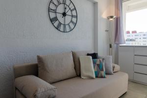 eine Uhr an der Wand über einer Couch im Wohnzimmer in der Unterkunft Holiday Home Slavia New 810 z widokiem na morze in Misdroy