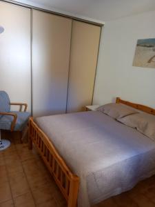 a bedroom with a large bed and a chair at Hélios 24, T2 climatisé, parking, terrasse, 500m plage in Cap d'Agde