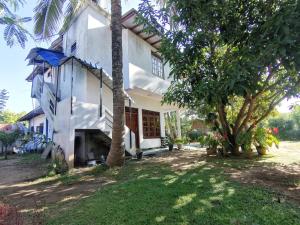 een wit huis met een palmboom ervoor bij Mango Shade Weligama in Weligama