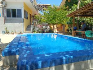 a swimming pool with a blue tiled floor and a house at Paziflora Hostel in Puerto Escondido