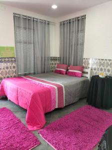 a bedroom with a pink bed with two pink rugs at Apartamento Cavaleiro in Nazaré