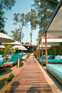 a wooden walkway with blue and white benches and umbrellas at Pause By The Sea in Morjim